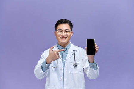 Male on-line doctor man show screen on mobile phone isolated on purple background.の写真素材