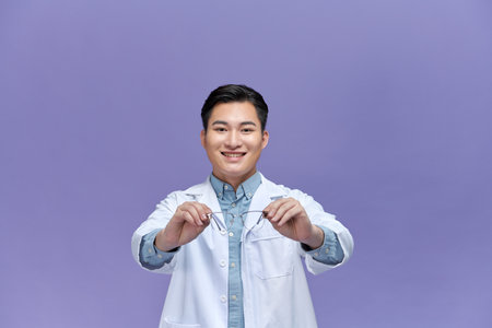 Male optometrist holding eyeglasses over purpleの写真素材