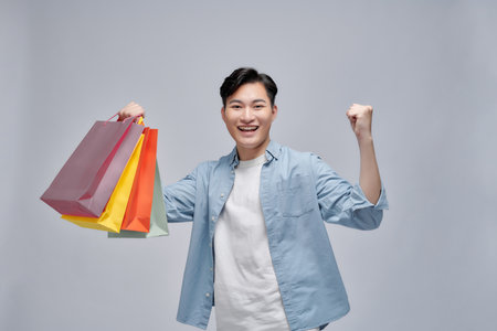 Excited man showing shopping bags and rejoicing from discounts,の写真素材