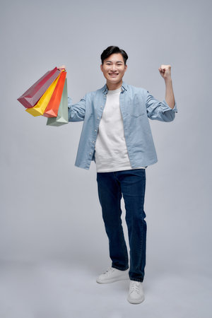 Excited man showing shopping bags and rejoicing from discounts,の写真素材