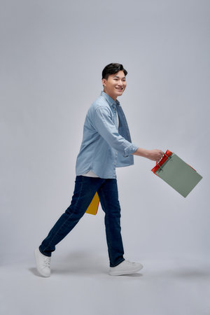 Photo portrait smiling man keeping bags in shopping mall isolated gray color backgroundの写真素材