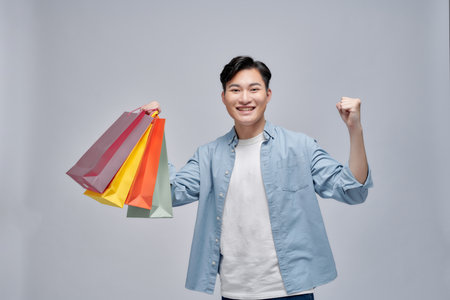 asian man smiling and holding the shopping bags on white isolated backgroundの写真素材