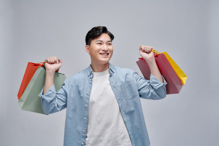 Asian young man holding shopping bags, full length portrait isolated.の写真素材