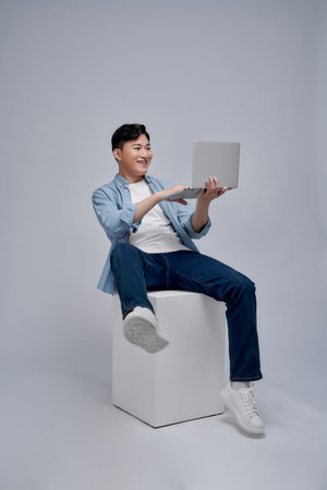 The young adult Asian man sitting the platform on the white background.の写真素材