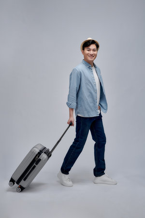 Happy young Asian tourist man holding baggage going to travel on holidaysの写真素材