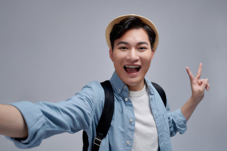 Self portrait of cheerfu blogger showing peace symbol with two fingers to the camera, making video...