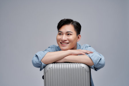 Traveler asian man sitting with suitcase isolated over white backgroundの写真素材