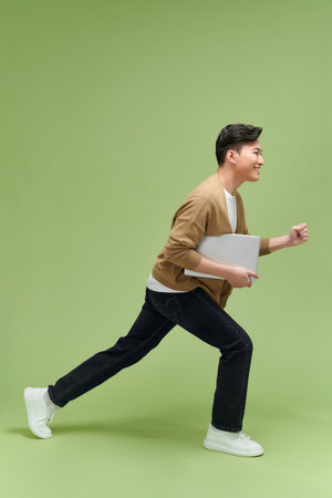 Full length image of young Asian businessman on green backgroundの写真素材