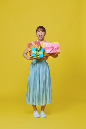 isolated portrait of asian smilimg woman holding heap of gift boxes.の写真素材