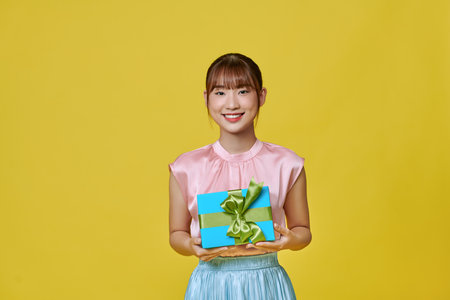 Beautiful girl posing with gift and smiling, showing wrapped present boxの写真素材