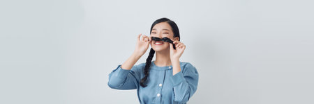 attractive playful girl grimacing making mustache isolatedの写真素材