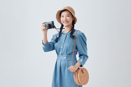 Young girl taking a picture with a small camera on a white backgroundの写真素材