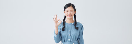 Pretty teen model lady showing okey symbol expressing agreement isolated on white backgroundの写真素材