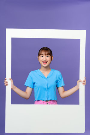 young lady dressed blue clothes smiling looking through white windowの写真素材