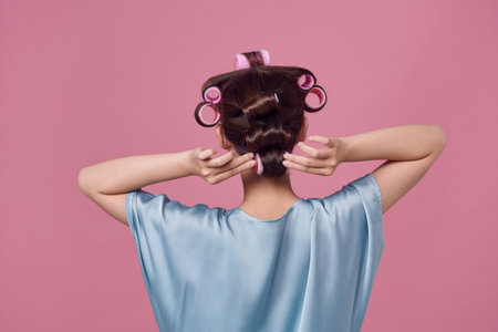 Beautiful young woman in hair rollers on light background, closeupの写真素材