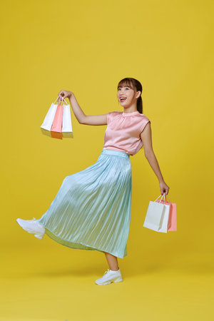 Full size profile photo of excited energetic person hands hold buyings isolated on yellow backgroundの写真素材
