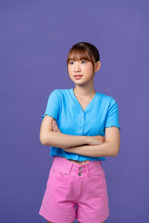 Young asian woman isolated on purple background with arms crossed and happyの写真素材