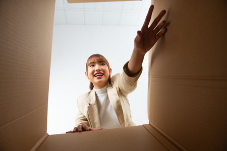 Smiling young woman opening a carton box, relocation and unpacking concept