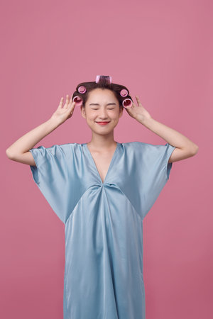 Beautiful woman with hair-curlers doing funny facesの写真素材