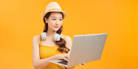 Young woman wear hat using laptop pc computer doing online booking tourの写真素材