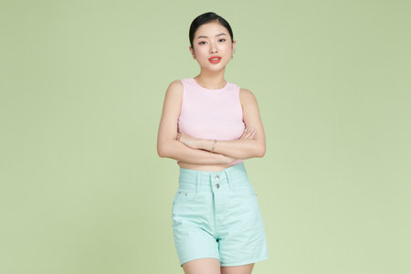 Confident nice smiling asian woman cross arms chest confident on light green backgroundの写真素材