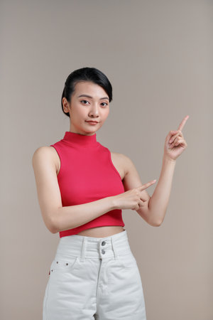 pretty woman smiling and pointing to side and upwards with both hands showing object in copy spaceの写真素材