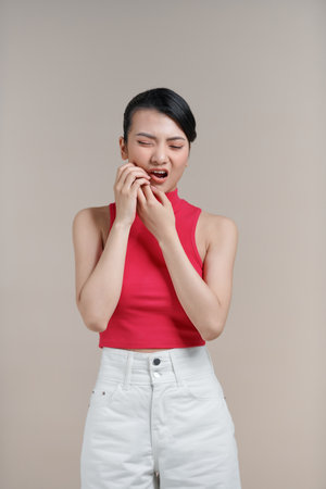 Beautiful Asian woman has a toothache isolated on beige background.の写真素材