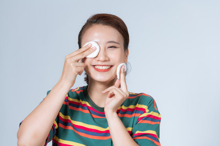 Woman using cotton pad. Happy smiling beautiful young woman cleaning skin by cotton pad.の写真素材