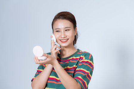 Woman using powder to touch up on her faceの写真素材