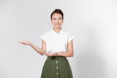 Portrait Asian woman is smiling and shows her hands to present something on the white background.の写真素材