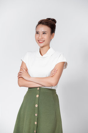 Smiling young beautiful Asian businesswoman doing arm crossed gestures in isolated studio white backgroundの写真素材