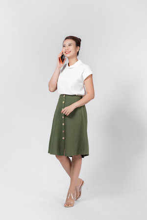 Happy woman calling on the smart phone on a white wallの写真素材