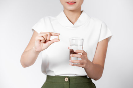 Pretty woman taking white pill on white backgroundの写真素材