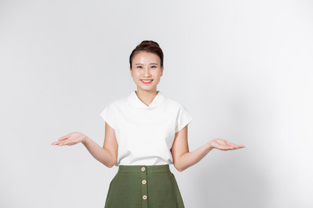 Young Asian woman raised her left and right hand to compare or demonstrate the product in copy spaceの写真素材