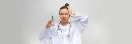 Young woman holding syringe stressed and frustrated with hand on head, surprised and angry faceの写真素材