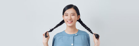 young female playing with her braids looking away isolated on white