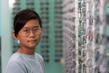 An asian boy trying on glasses in an optician store.