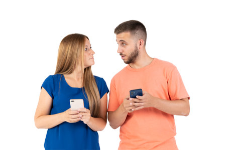 A young couple on a white background looking at the smartphone.の写真素材