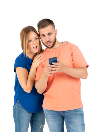 A young couple on a white background looking at the smartphone.の写真素材