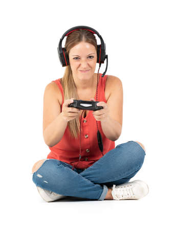 Young woman playing videogames with a controler and a headphones in a white backgroundの写真素材