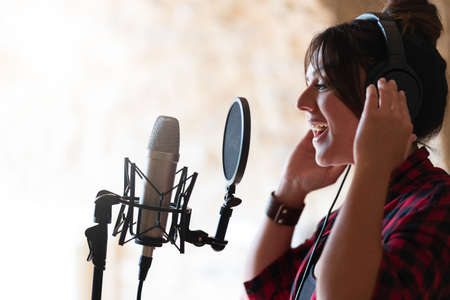 Professional singer woman recording a song in a studioの写真素材