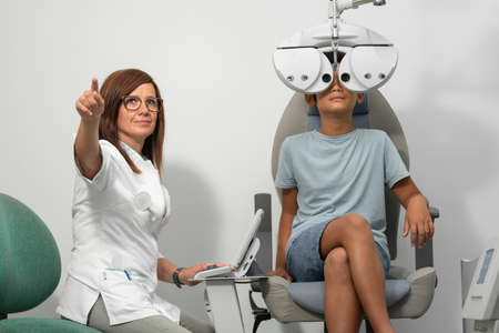 Asian boy with a phoropter at an optometrist consultationの写真素材