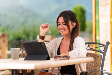 Woman sitting on a terrace writing on a tablet with digital penの写真素材