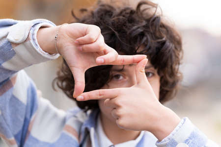 Young brunette woman with curly hair making the Framing sign with her handsの写真素材