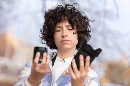 Young brunette woman with curly hair choosing a lens for her cameraの写真素材