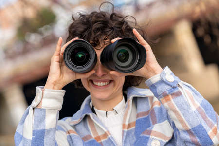 Young brunette curly hair woman fooling around with two photography lensesの写真素材