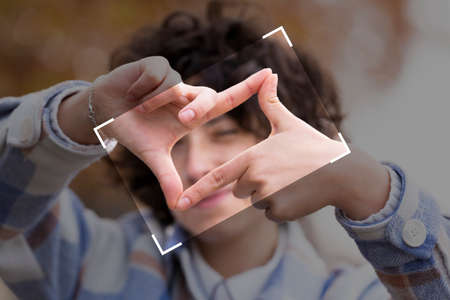 Young brunette woman with curly hair making the Framing sign with her handsの写真素材