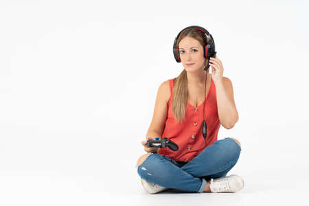 Woman playing video games with a controller and talking with headphones in a white background
