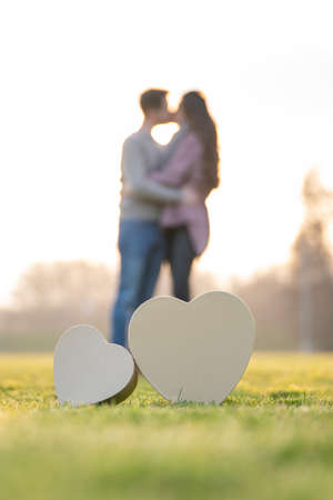 Young couple kissing behind two heart shapes in a park on valentines dayの写真素材