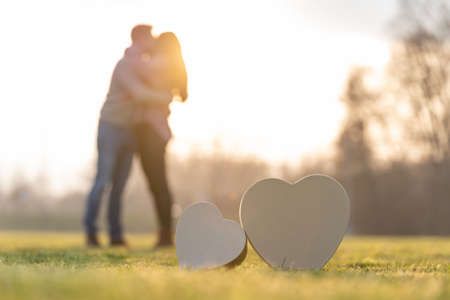 Young couple kissing behind two heart shapes in a park on valentines dayの写真素材